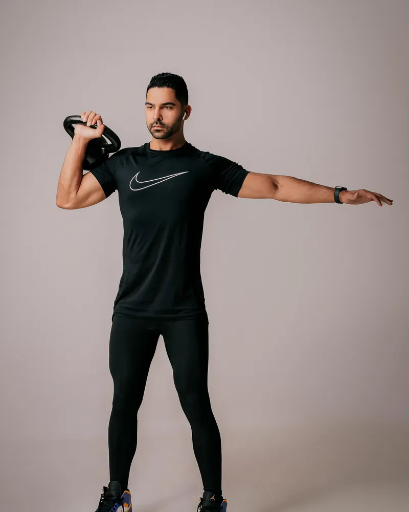 Homem de roupa de treino segurando um kettlebell