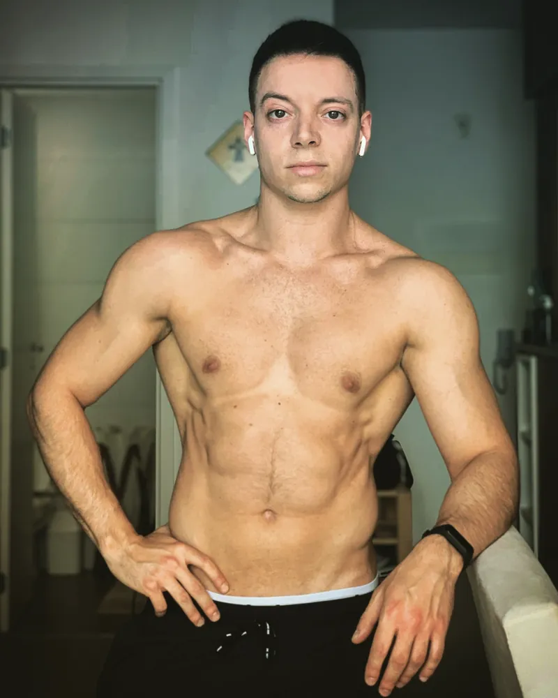 Rapaz sem camisa, com as mãos na cintura, mostrando o abdômen definido